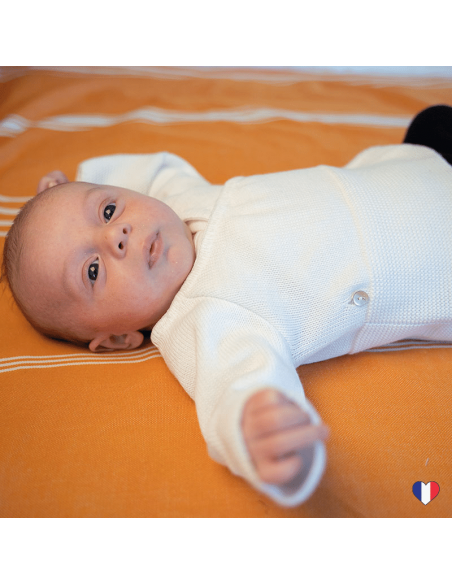 Brassière tricotée blanche sur bébé aux bras tendus écartés
